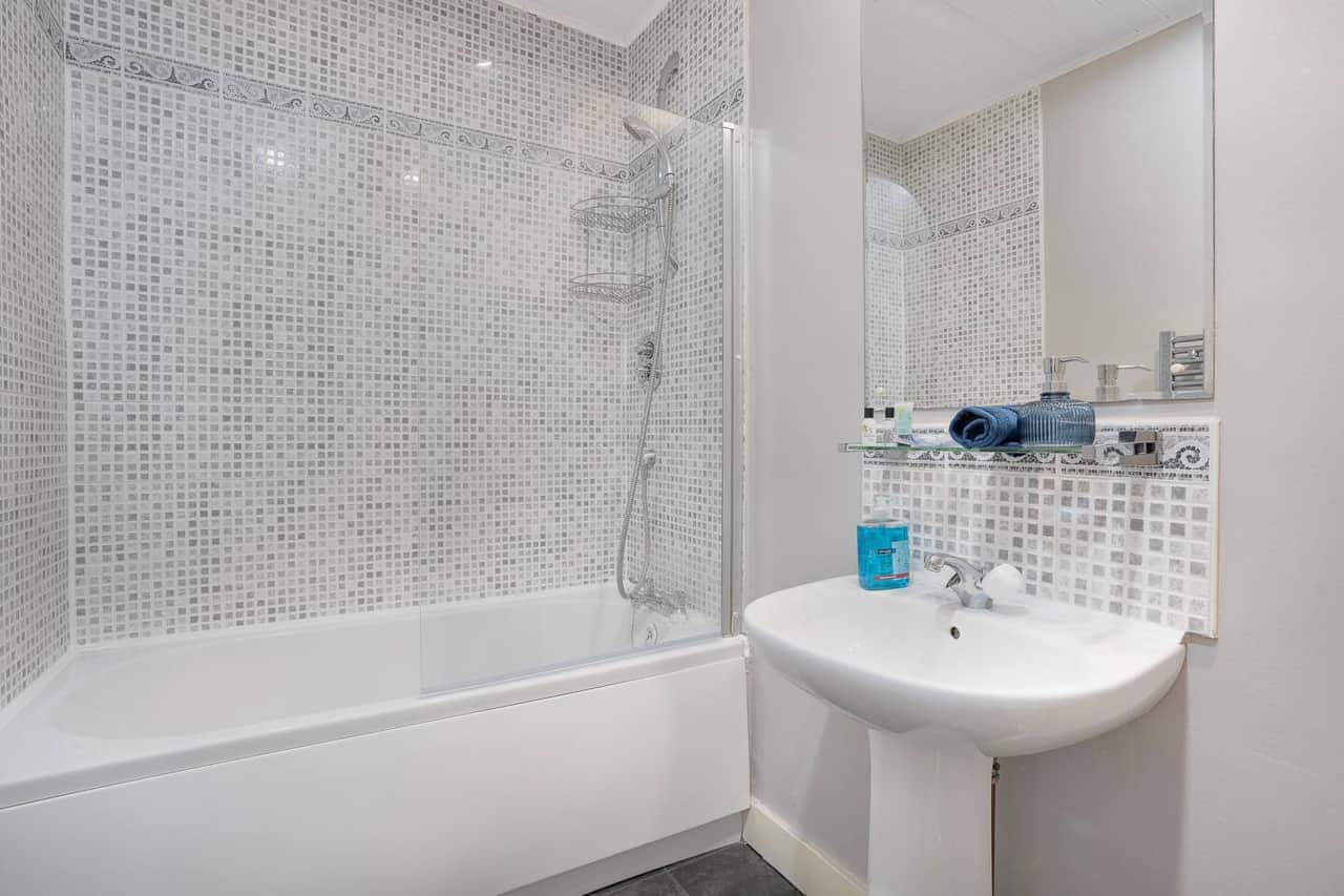 Clean, modern bathroom with a full-size bath and overhead shower, suitable for both quick mornings and relaxed evenings.