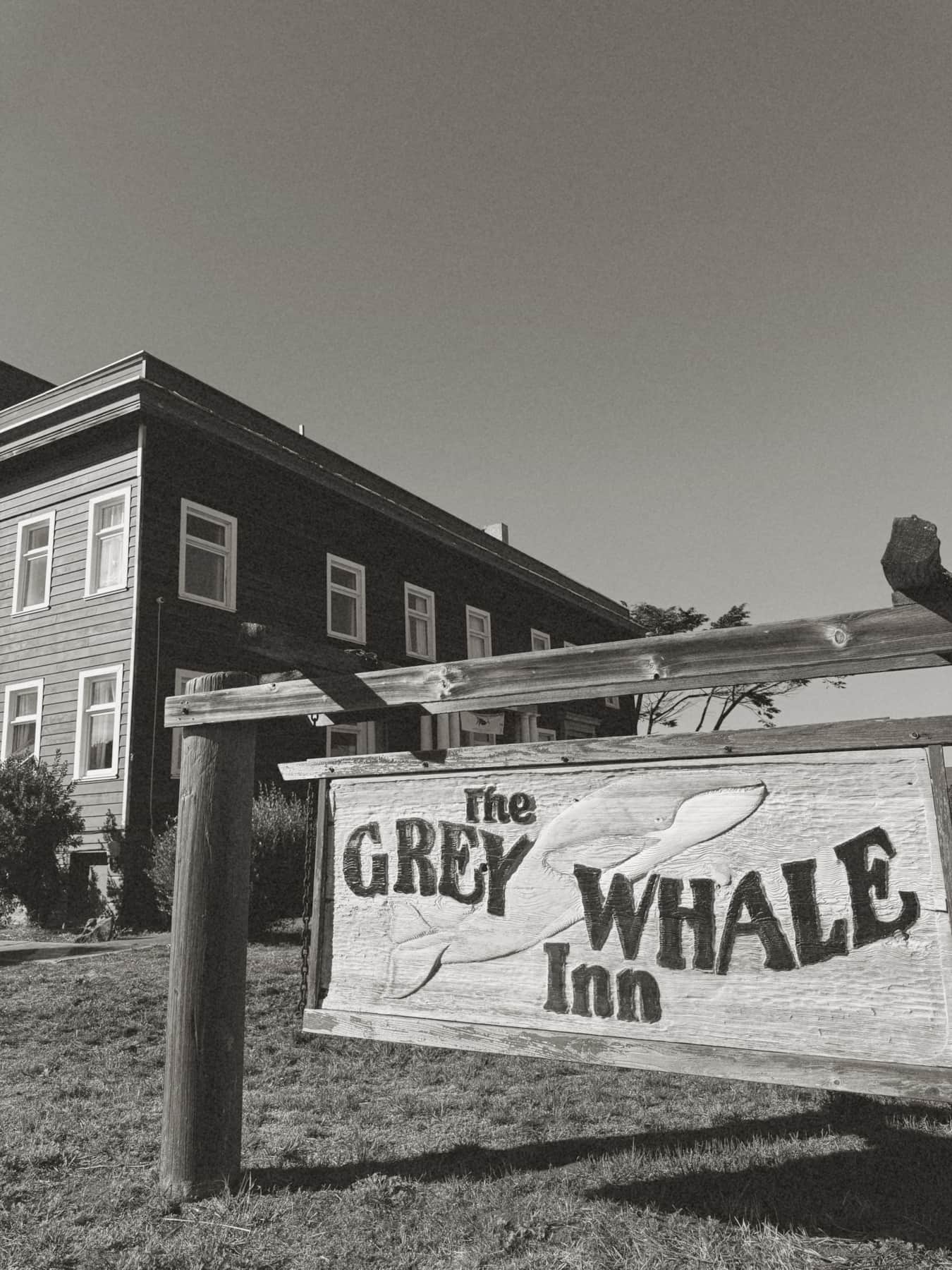 Exterior of The Grey Whale Inn in Fort Bragg CA, a historic redwood building with a hand-painted whale-themed sign.