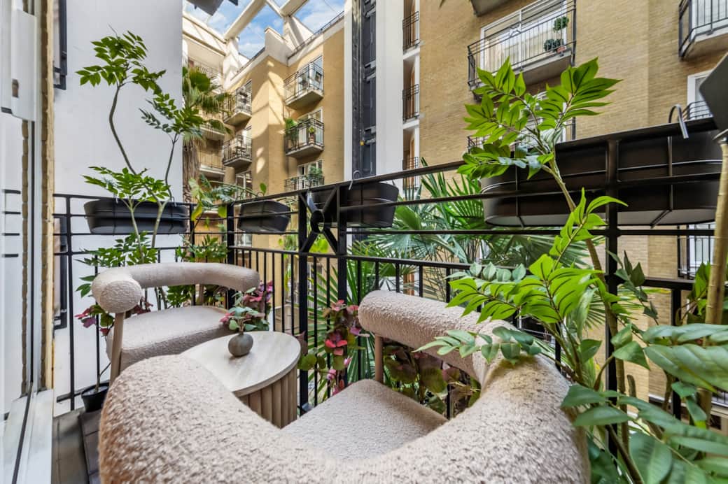 Leafy balcony with cozy seating, small table and courtyard views, creating a calm, inviting outdoor Leafy balcony with cozy seating, small table and courtyard views, creating a calm, inviting outdoor