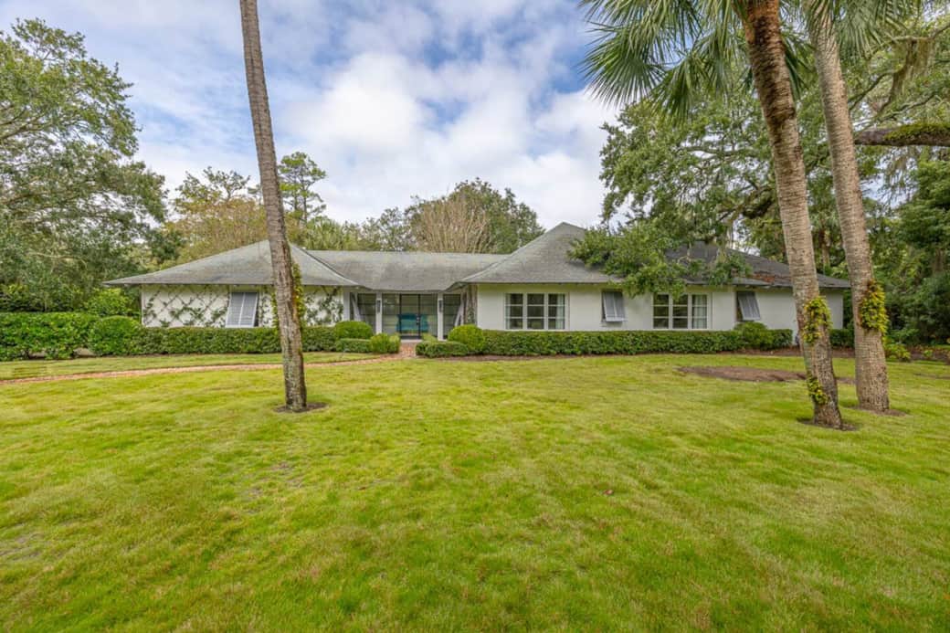 The property features a large front yard from the drive, to the house. This precious brick ranch features latticed ivy. 