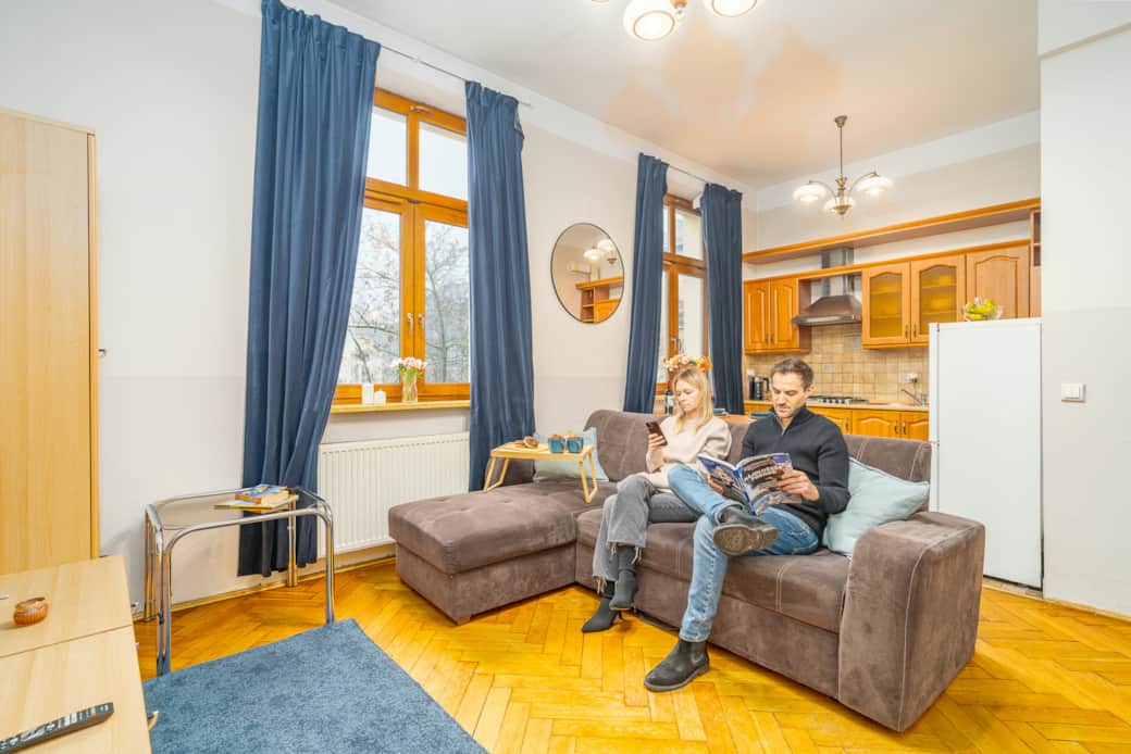 Bright living area with a comfortable sofa, kitchenette and large windows providing natural light.