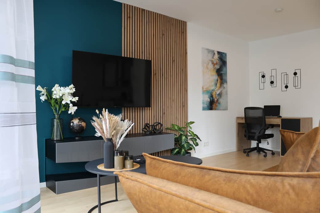 Wohnbereich mit 55"-Smart-TV, Schlafcouch (140 × 200 cm) und integriertem ergonomischen Arbeitsplatz