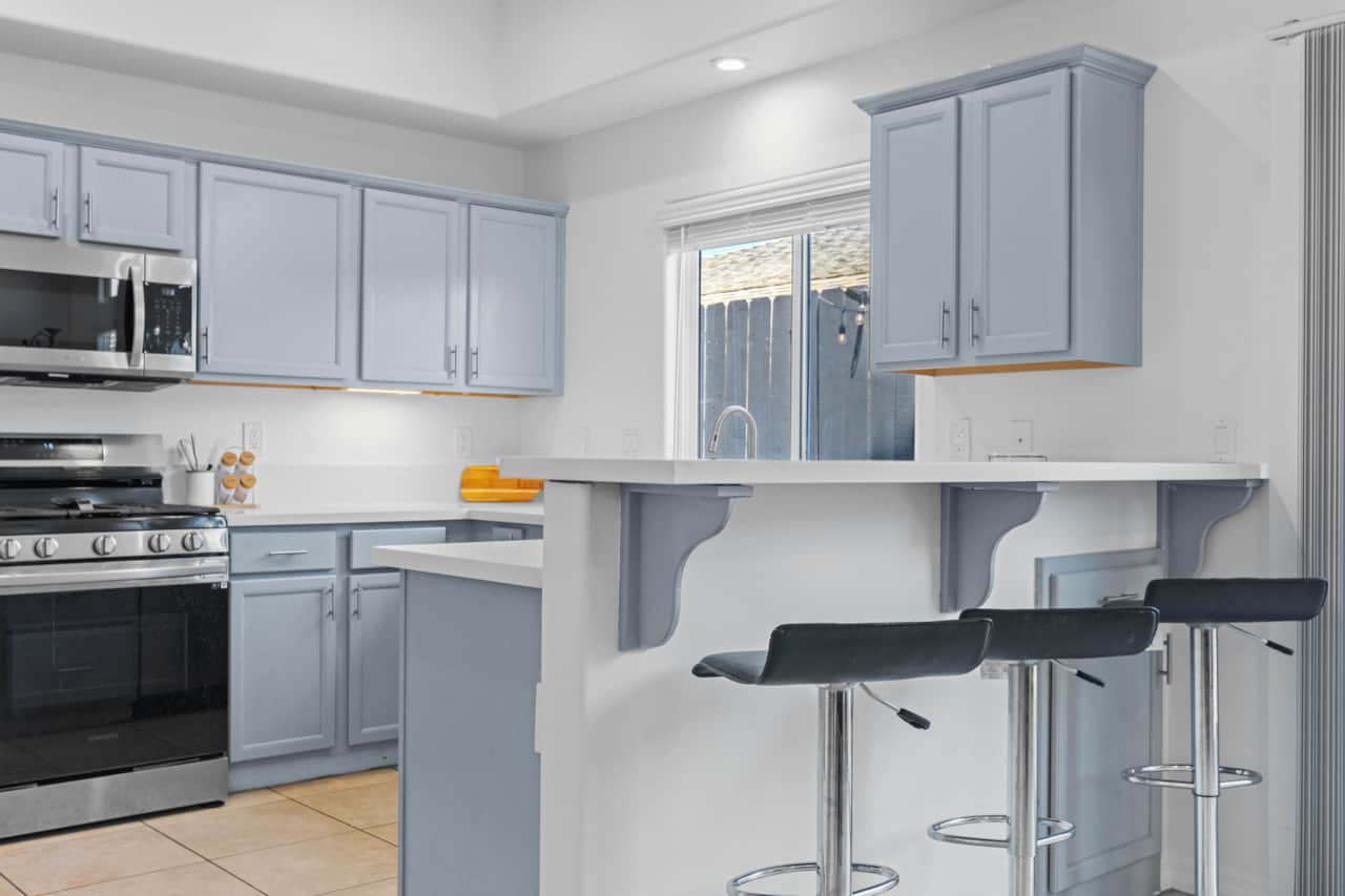 Kitchen with breakfast bar, sleek appliances, and stylish blue cabinets perfect for everyday cooking