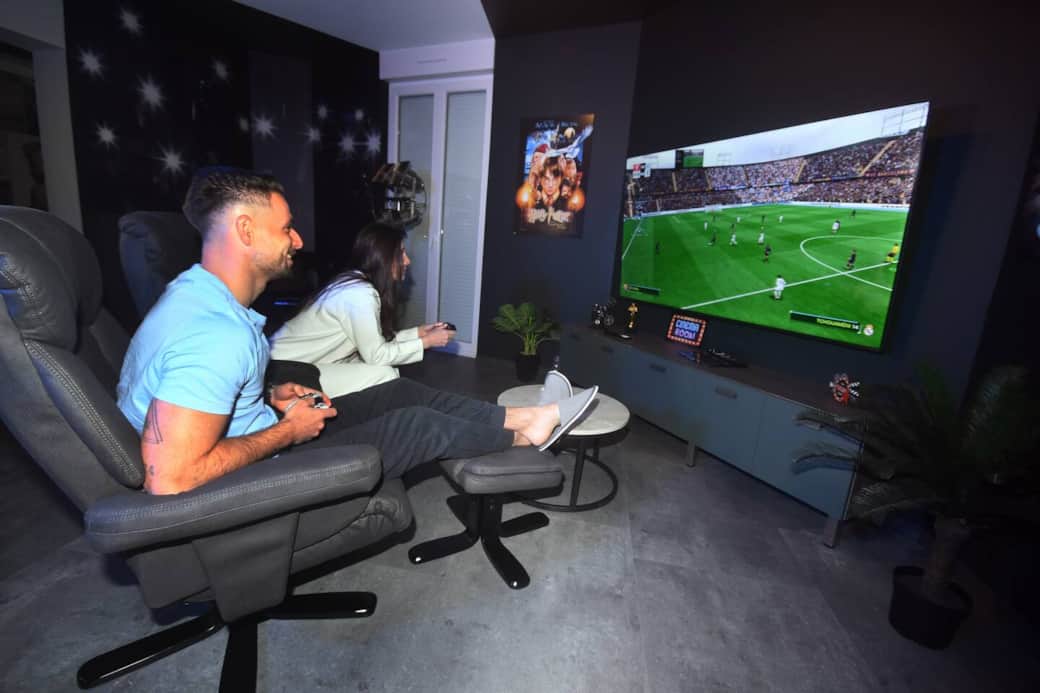 Salon immersif avec grand écran et espace repas convivial.
