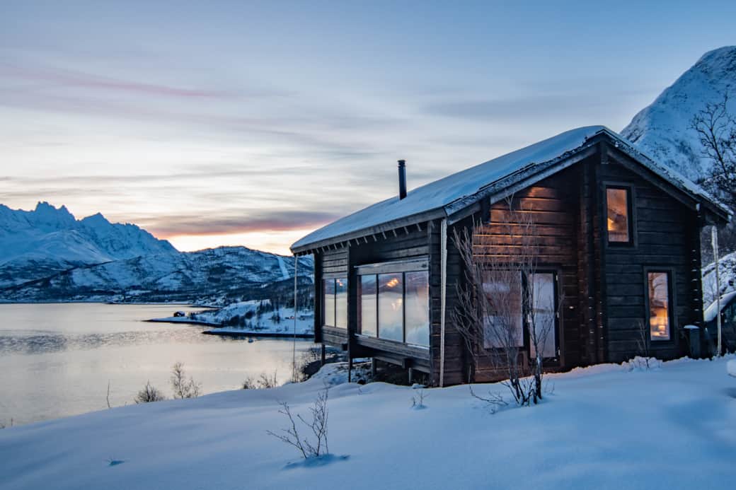 Winterliche Blockhütte am Fjord – Ferienhaus Tind in Nordnorwegen bei Sonnenuntergang