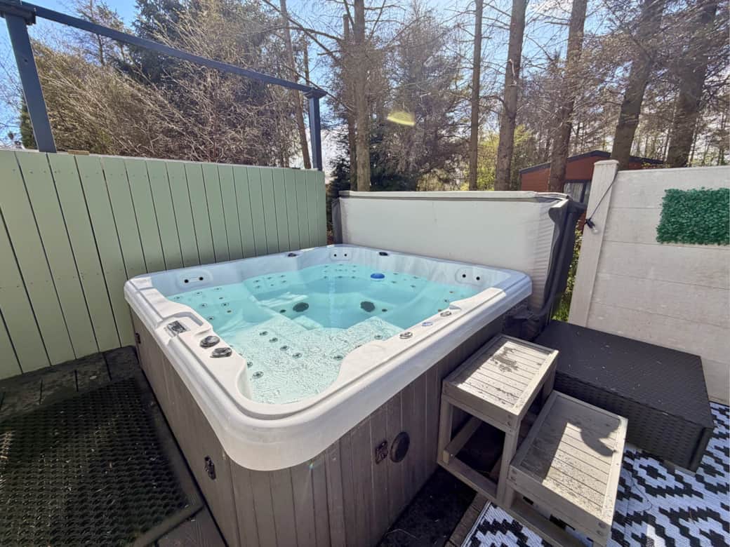 Spacious outdoor area with two decking levels, private all-weather hot tub, outdoor dining table