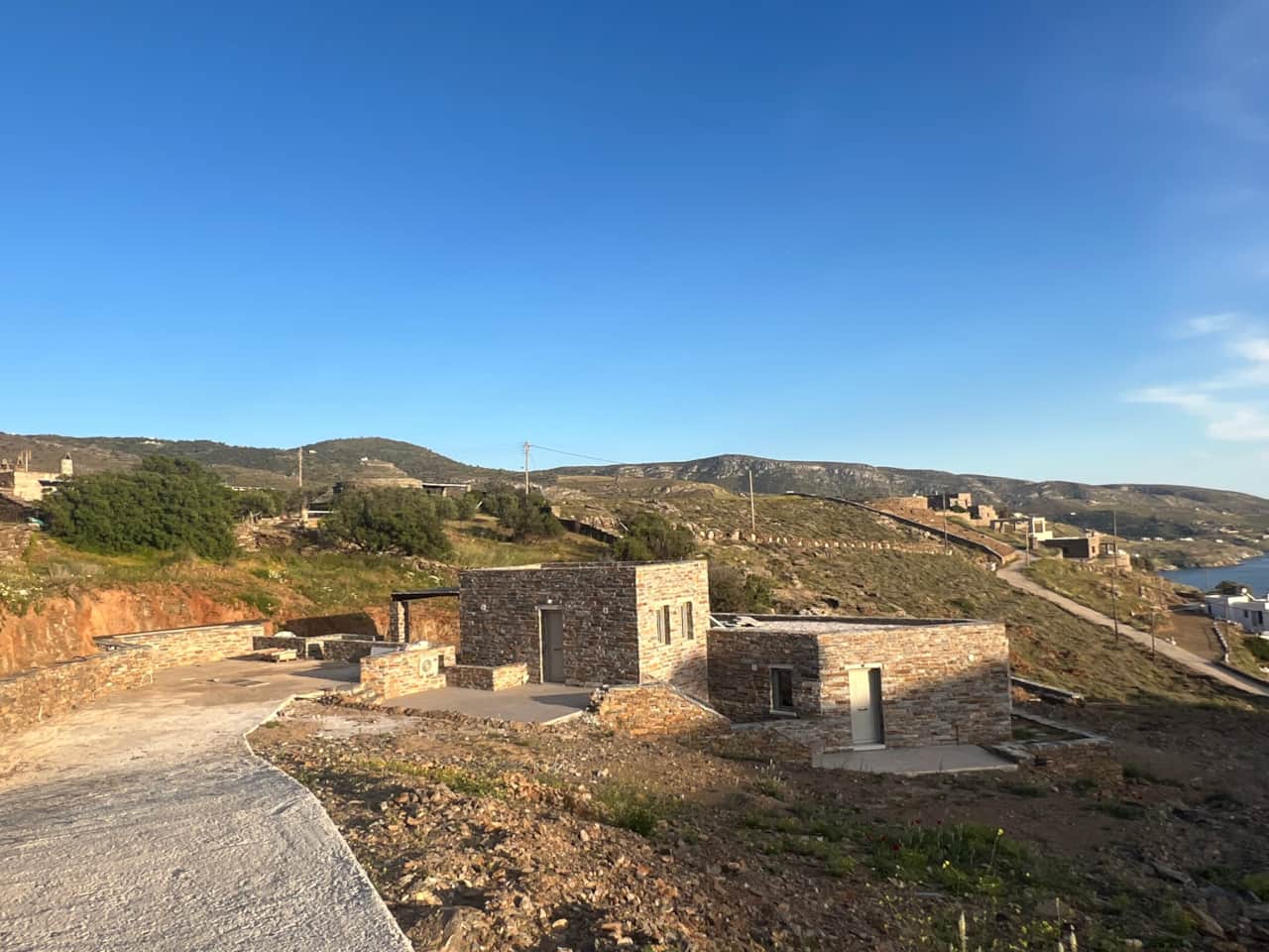 Private gravel road leading down to stone lodgings on the hillside, Koundouros, Kea