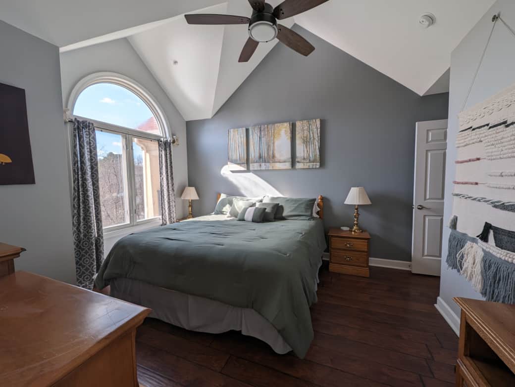 The primary bedroom has natural light flooding in from large windows.