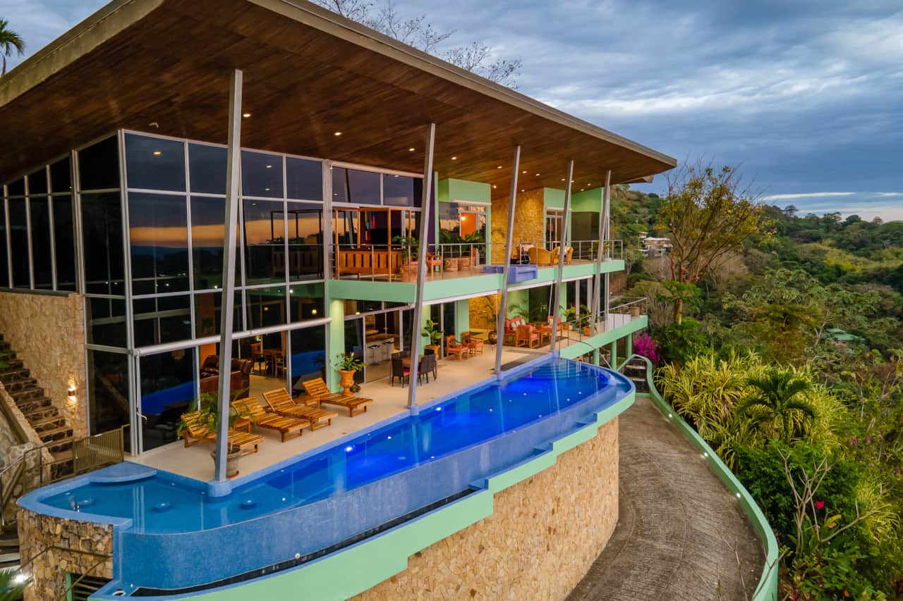 The villa has floor to ceiling glass windows and doors, expansive covered terraces and infinity pool