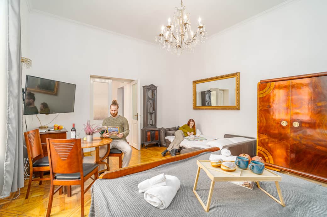 The space is bright and functional, featuring a comfortable bed and a fold-out sofa.