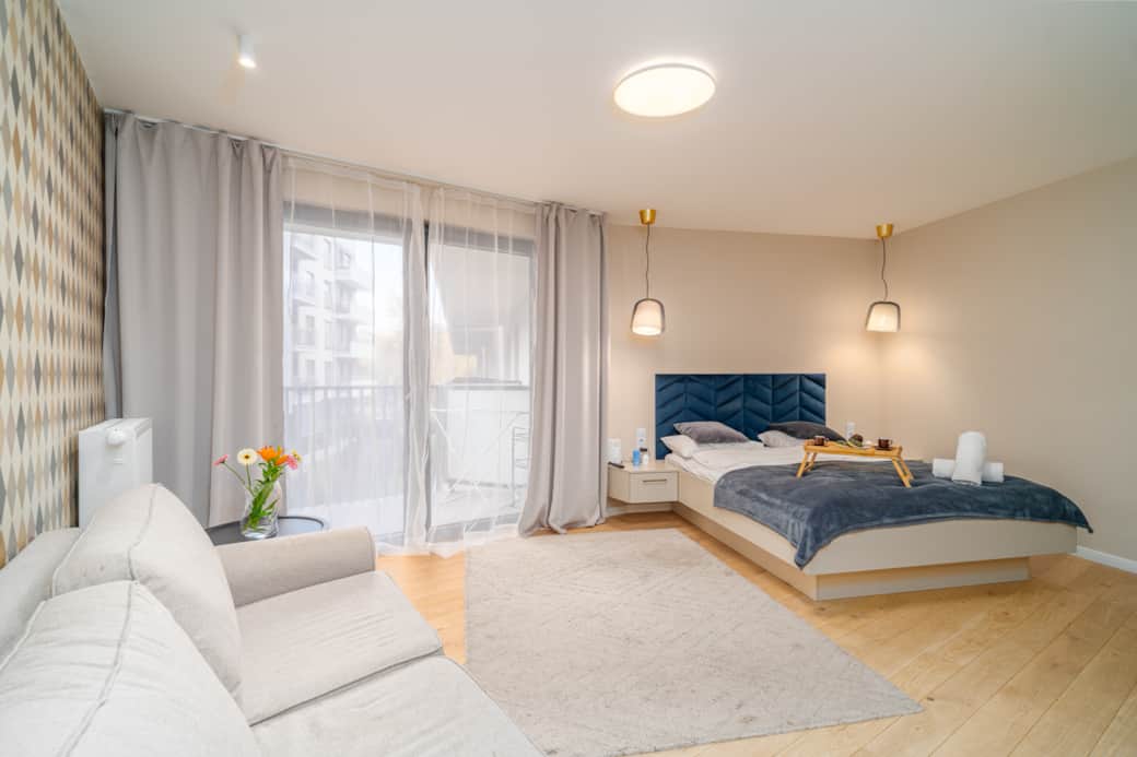 Przestronny pokój z dużym łóżkiem i granatowym zagłówkiem.