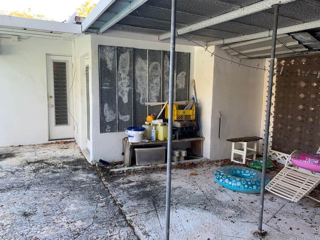 Casa Citron service area before renovation showing cluttered pool supplies and unfinished space