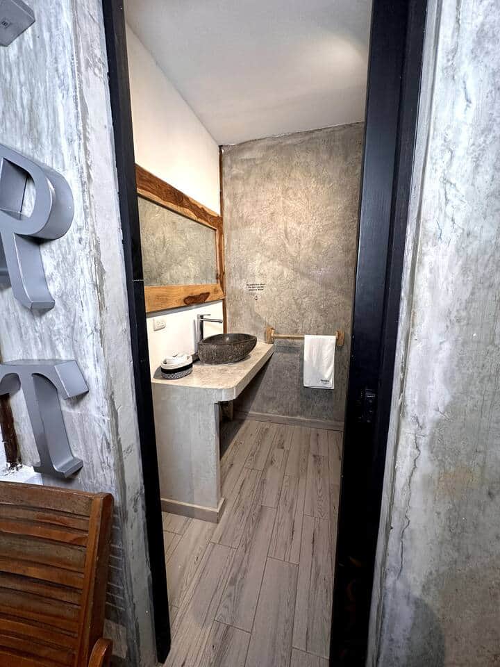Stone sink and wood-framed mirror glimpsed through the bathroom doorway at Saboga Lodge