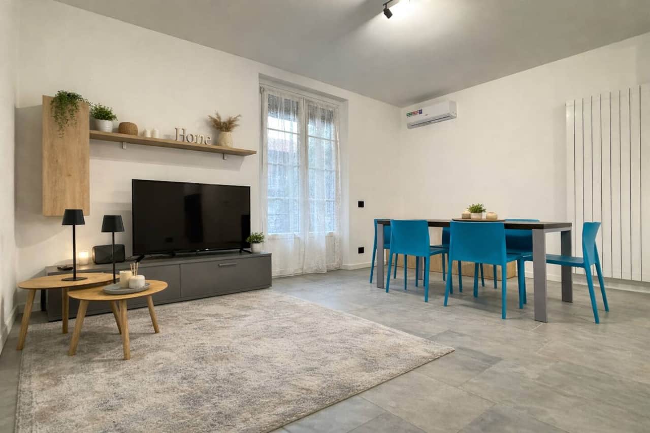 Salotto ampio e luminoso in stile moderno, con spazi ben distribuiti e atmosfera rilassante, arricchito da un divano blu, Smart TV e zona pranzo con tavolo e sedie coordinate, ideale per pasti o lavoro in tranquillità.