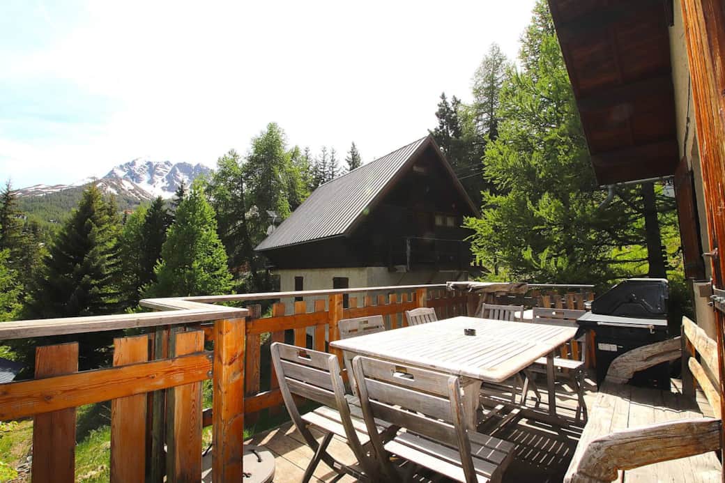 La terrasse du haut à côté du salon, avec une table à manger, des mange debout, et un barbecue à gaz.