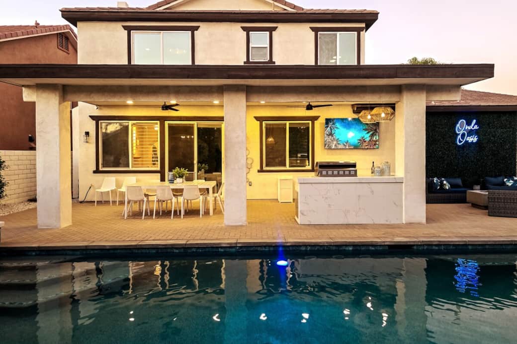 Exterior view of back of home.  A relaxing retreat and oasis! Enjoy the 75” Smart TV, BBQ, and outside meals under the covered patio, or the fire pit with cozy couches. 