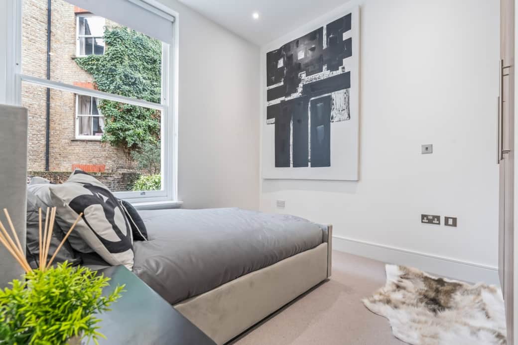 Calm, modern bedroom with a comfortable upholstered bed, fresh linens, stylish artwork and natural light for a restful night’s sleep.