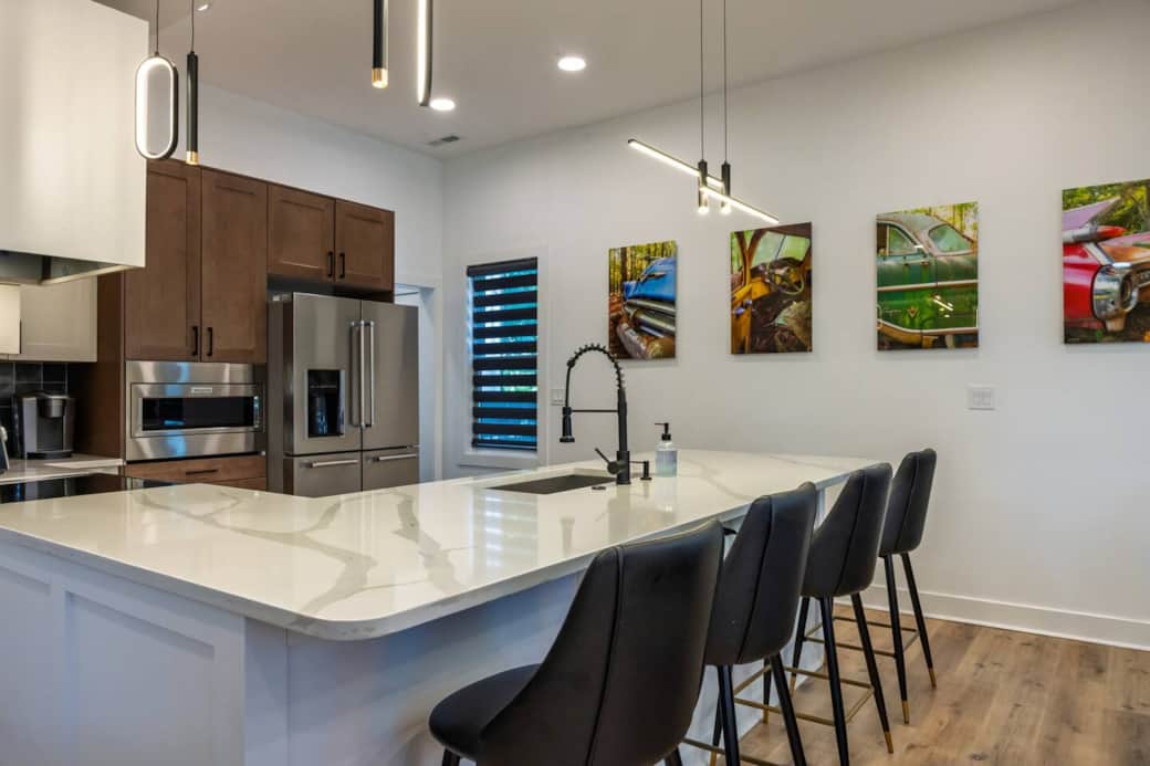 Expansive kitchen peninsula covered in white quartz with bar seating for four guests. More original photography on the walls provide a gallery-like feel.