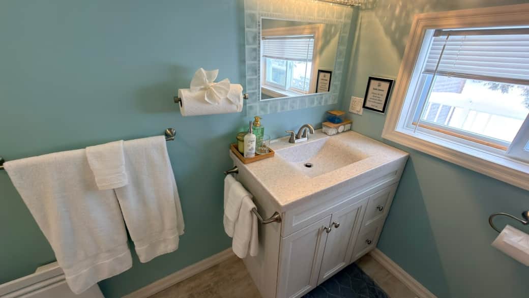 Bright and spotless full bathroom with a shower–tub combo, fresh towels, and complimentary toiletrie