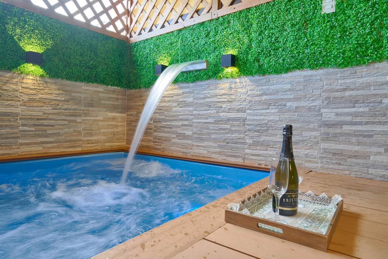 Un rincón relajante y privado, donde el sonido de la cascada y el azul del agua invitan a desconectar y  La combinación de piedra y verde aporta frescura, creando un espacio íntimo y tranquilizante.