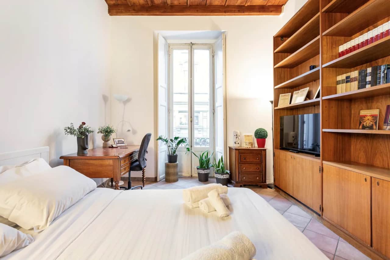 Schlafzimmer mit Bett, Bücherregal und Fenstern, in Mailand