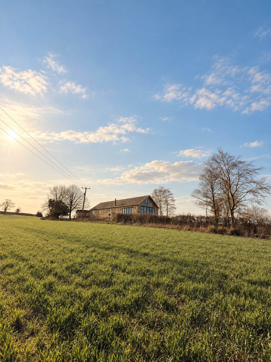 The detached stone Cotswold Barn with its lawn, terrace and driveway