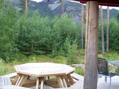 Auf der Terrasse steht ein großer, achteckiger Holztisch, der nicht wirklich transportabel ist. Daneben gibt es einen weiteren Tisch mit Stühlen, einige Liegen und einen Holzkohlegrill.