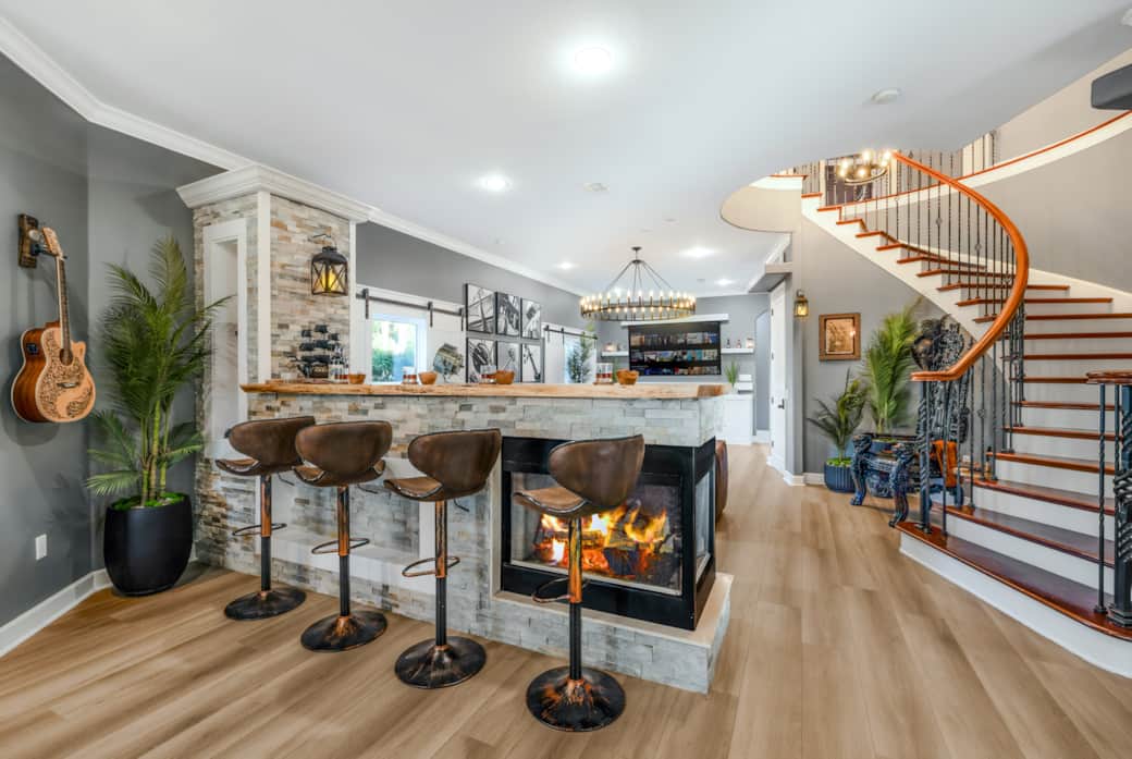 Cozy fireplace bar with a view of the living room and dramatic spiral staircase centerpiece. Cozy fireplace bar with a view of the living room and dramatic spiral staircase centerpiece.