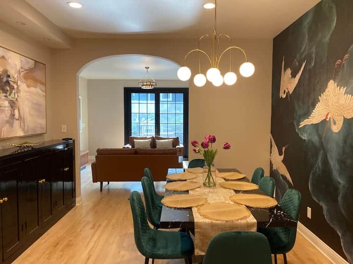 Elegant dining area with statement crane mural and modern chandelier.