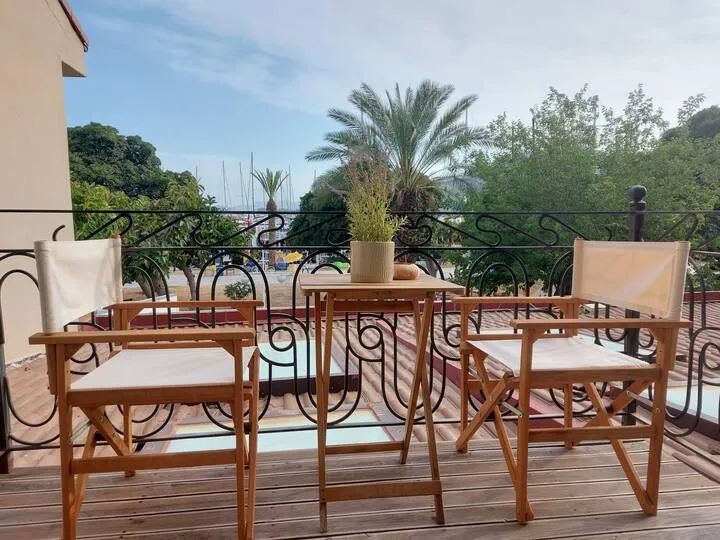 Balcony with two wooden chairs and a small table, overlooking greenery and a marina, Apart Guney 7, Gocek