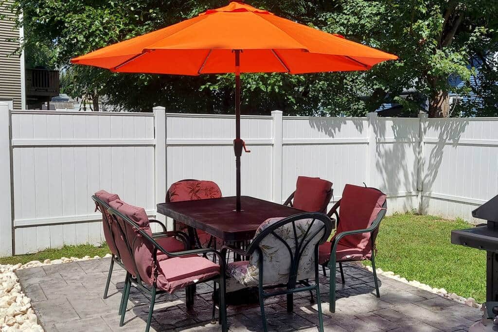 Patio table set with solar-powered umbrella for night-time lighting.