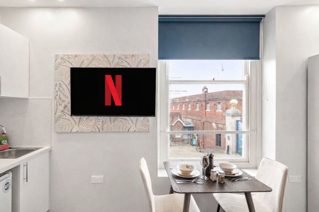 A stylish open-plan dining space with a sleek wall-mounted Smart TV and elegant seating for two. A stylish open-plan dining space with a sleek wall-mounted Smart TV and elegant seating for two.