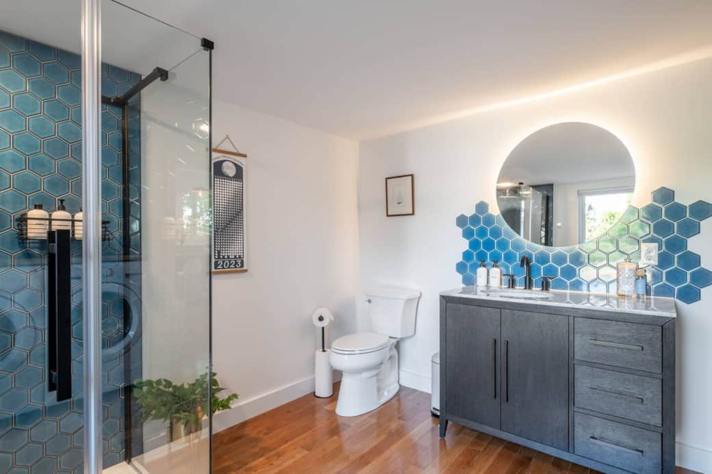 The tile from the shower accents the backlit mirror in the main floor bathroom. 