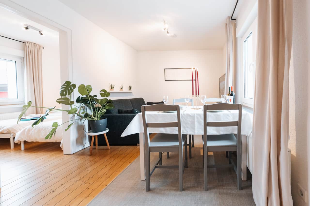 Essbereich mit Tisch für vier Personen, dahinter die Sofaecke.