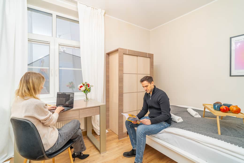 Bright bedroom with two single beds, work desk and wardrobe, ideal for rest or work.