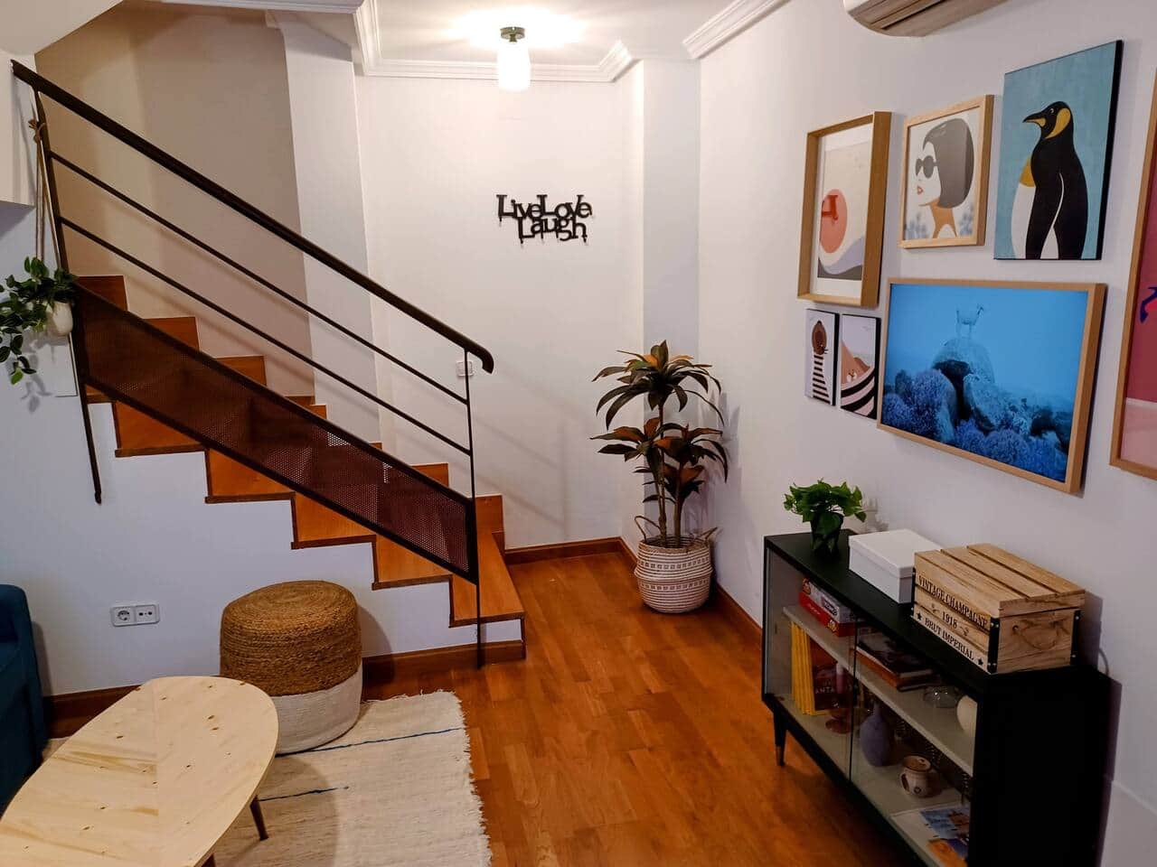 Escalera de madera y zona de estar con láminas