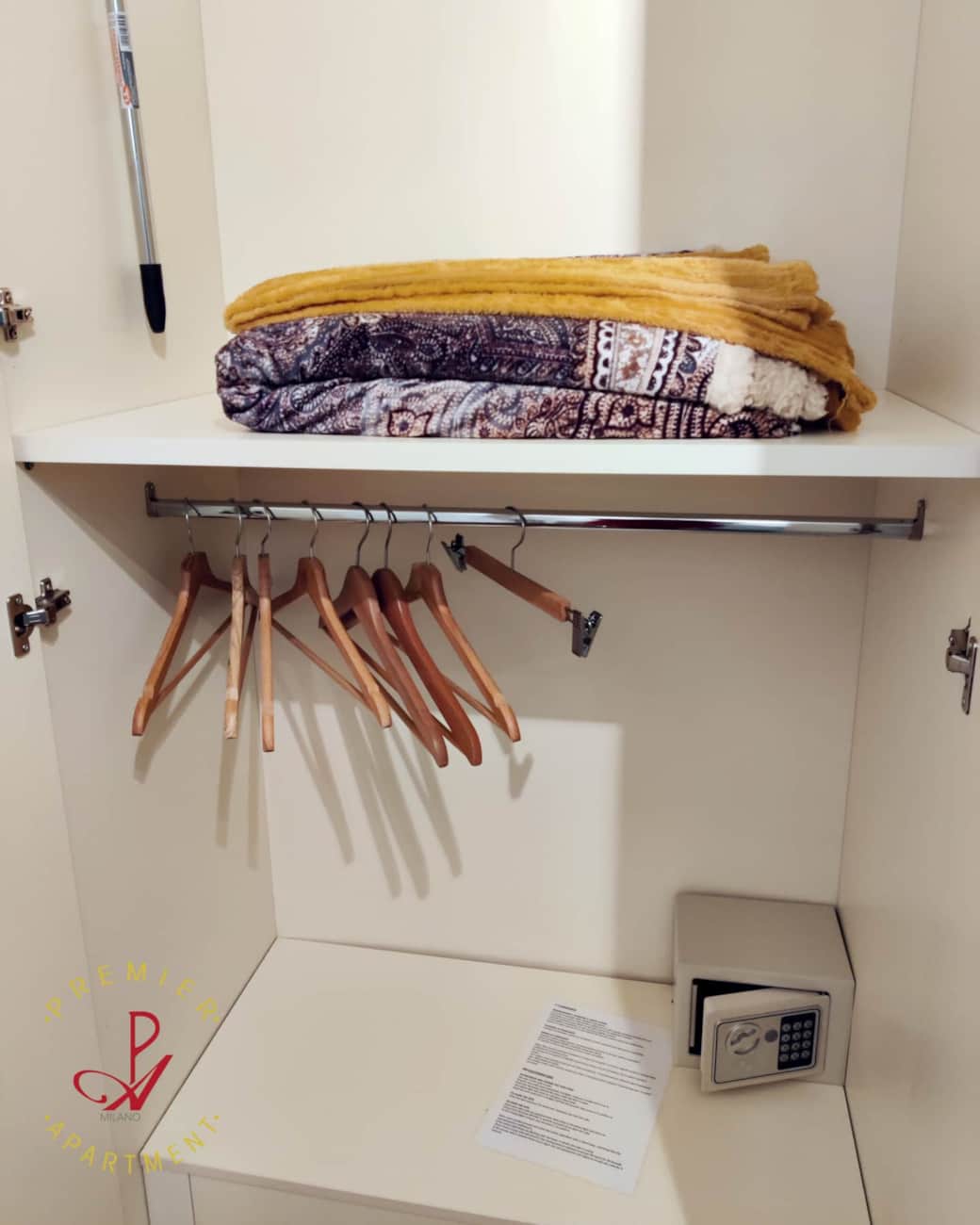 Interior del armario del dormitorio con perchas, manta extra y caja fuerte.