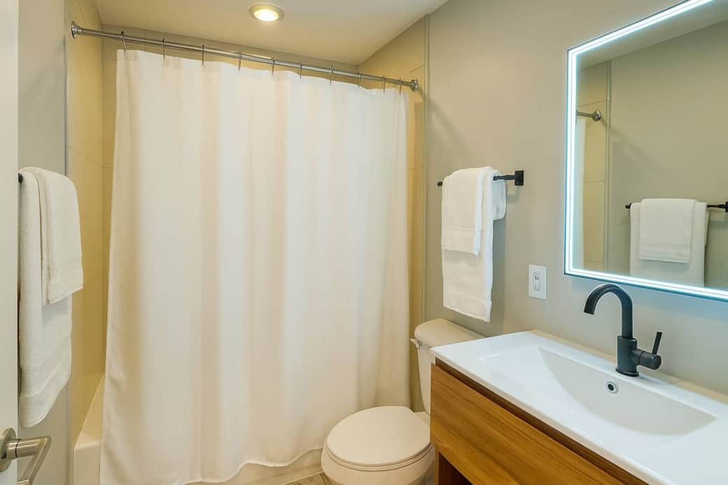 Modern bathroom with a lit mirror, beige accents, and fresh white towels — bright, clean, and relaxing.