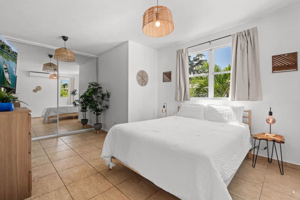 Spacious primary bedroom with queen bed and tropical views