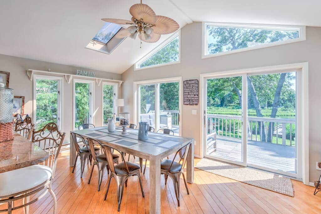 Dining room with a cathedral ceiling, a long table and sliders to the deck