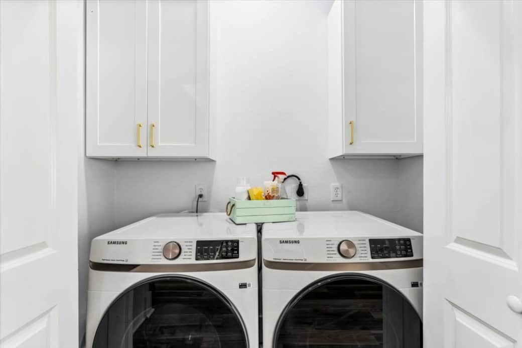 Laundry room with full size front load washer and dryer. Cleaning supplies and detergents are available for use