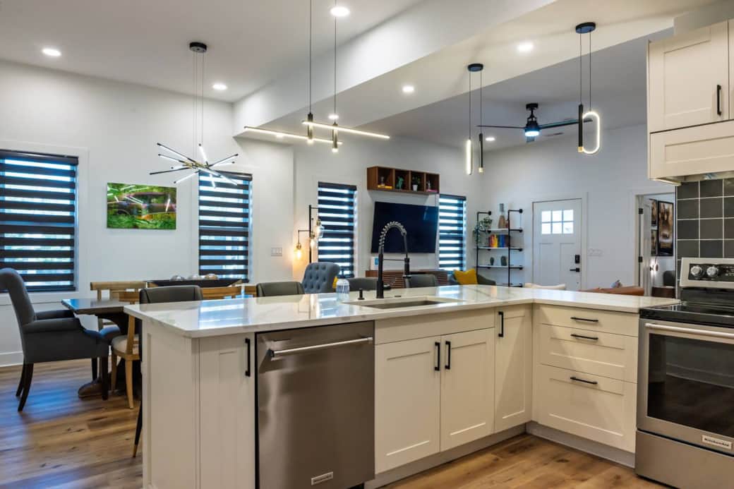 Modern, sleek well-stocked kitchen with white quartz countertops, range with convection oven, microwave, dishwasher, and full-size fridge for a seamless dining experience.