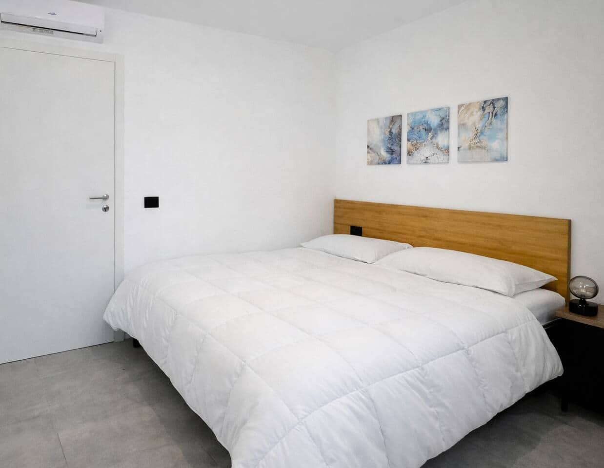 Camera luminosa e ordinata in stile moderno con letto matrimoniale, arredi in legno e dettagli blu che creano un’atmosfera rilassante. 