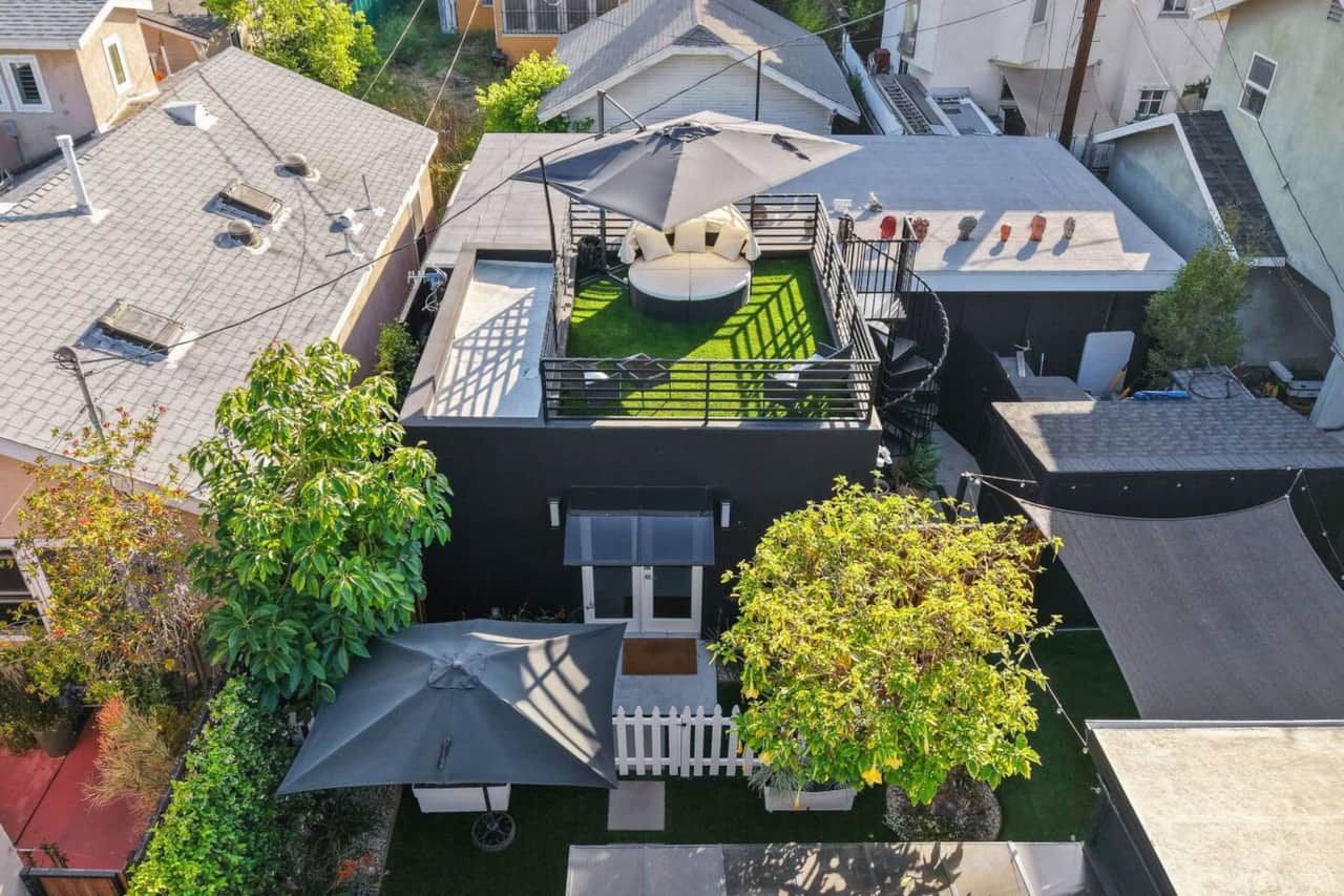 Aerial view showcasing the private yard, patio seating, and rooftop lounge setup.