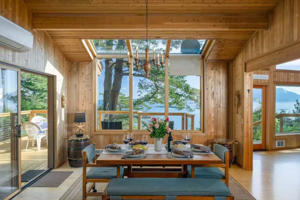 Enjoy meals with stunning views of Rosario Strait from this bright dining area, featuring a skylight, warm wood accents, and easy access to the deck for indoor–outdoor dining. Enjoy meals with stunning views of Rosario Strait from this bright dining area, featuring a skylight, warm wood accents, and easy access to the deck for indoor–outdoor dining.