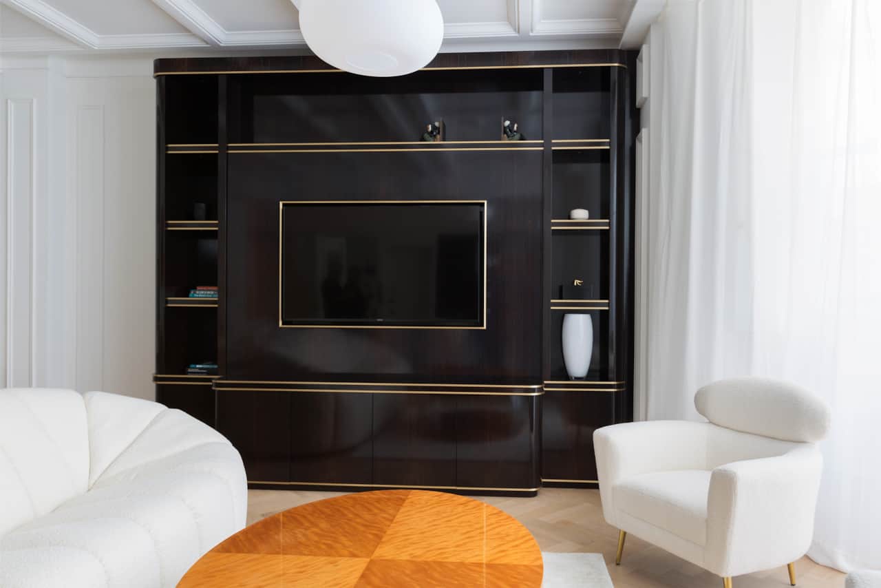 Dark lacquered entertainment unit with brass trim and mounted TV