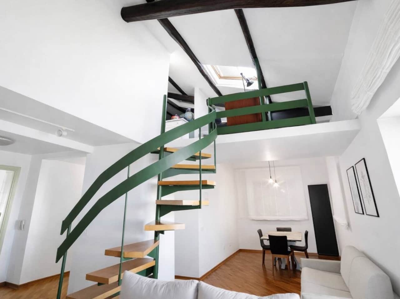 Scala dal design moderno con struttura verde e gradini in legno, che collega armoniosamente il soggiorno al livello superiore, valorizzando l’architettura dello spazio.