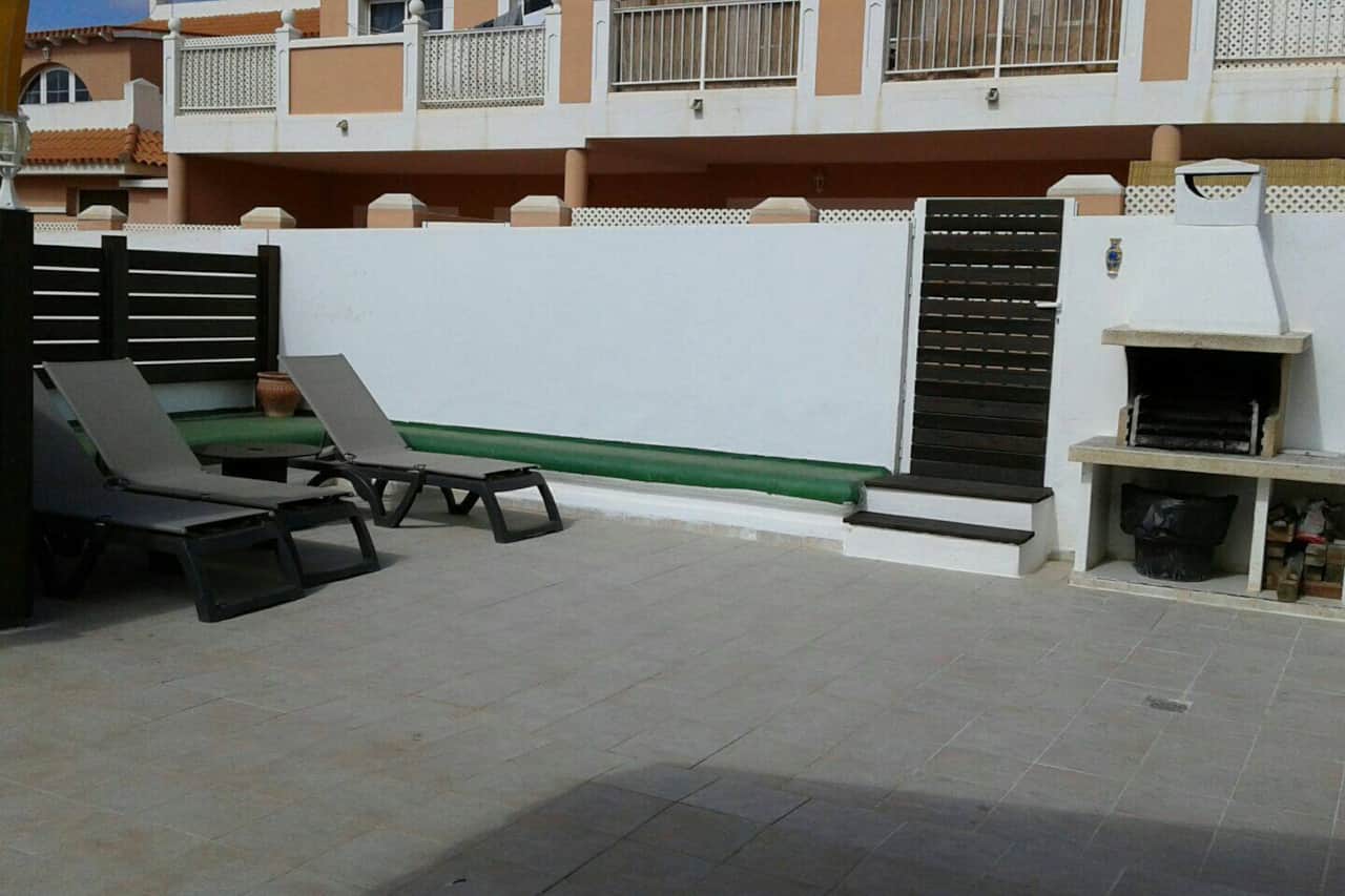 Terraza con tumbonas y barbacoa de obra