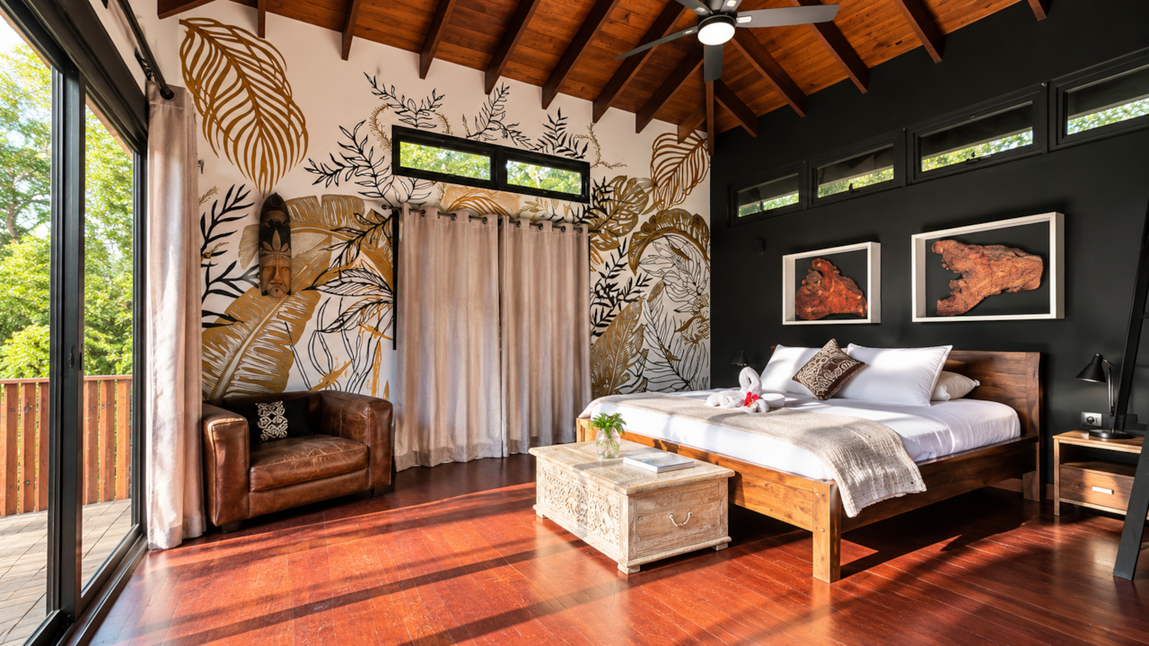 Master Suite con techo alto de madera, mural de selva y sillón de cuero, Villa Noelia