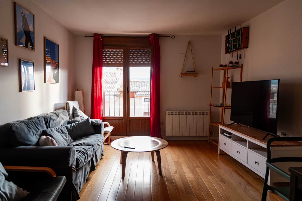 Salón con sofá, televisión y balcón